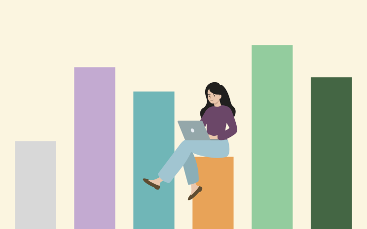 woman sitting on bar charts working on a laptop